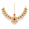 Gold-toned filigree necklace with red gemstone accents and dangling pearl-like beads, shown on a plain white background.