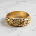 Gold bracelet with floral patterns on a marble surface