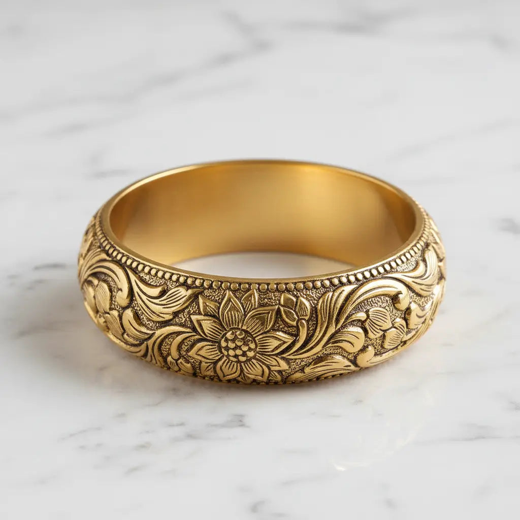 Gold bracelet with floral patterns on a marble surface
