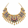 Ornate gold necklace with colorful gemstones on a white background