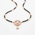 A black and rose gold beaded necklace with a central circular pendant featuring a heart-shaped clear gemstone and a dangling clear stone, set against a plain white background.