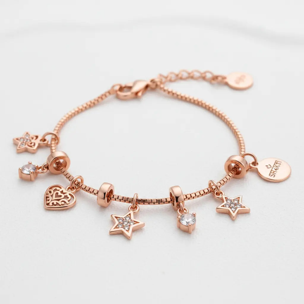 A rose gold charm bracelet featuring a beaded chain with dangling star, heart, and round charm elements, including a clear crystal and a round engraved tag that reads 'SKY&STAR'.